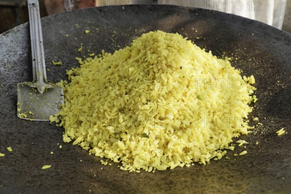 Kota, Rajasthan, North India, Asia, A large pile of poha in an iron pan with a spatula next to it, India