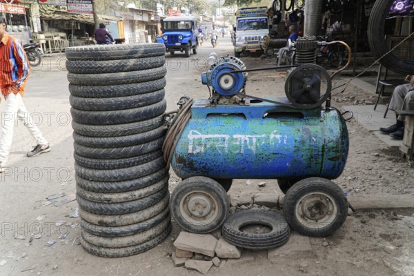 Kota, Rajasthan, North India, Asia, A pile of tyres next to a blue compressor in a dusty workshop environment, India