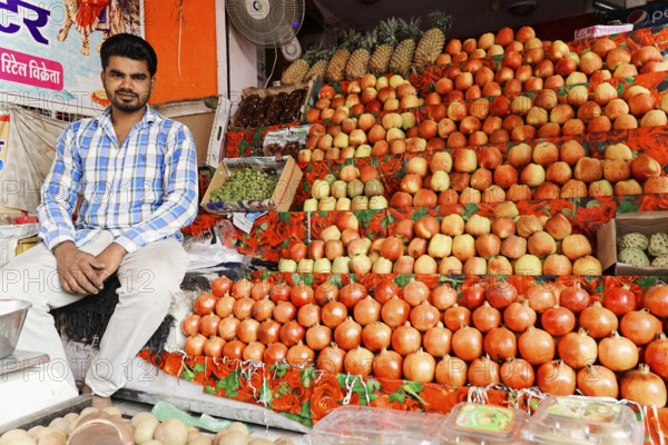 Kota, Rajasthan, North India, Asia, Vendor sitting at a market stall with a colourful selection of apples and other fruits, India