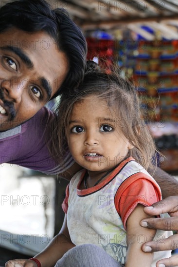 Kota, Rajasthan, North India, Asia, man with little girl, both smiling, in front of a colourful background, India