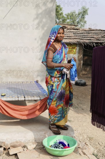 Kota, Rajasthan, North India, Asia, A woman in a colourful garment washes clothes in a rural courtyard, India
