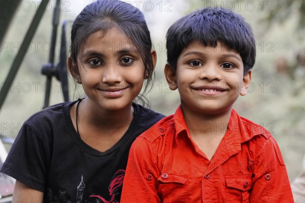 Ranthambhore Tiger Reserve, Sawai Madhopur, Kota, Rajasthan, North India, Asia, Two children smile into the camera. A girl in a black shirt and a boy in a red shirt, India