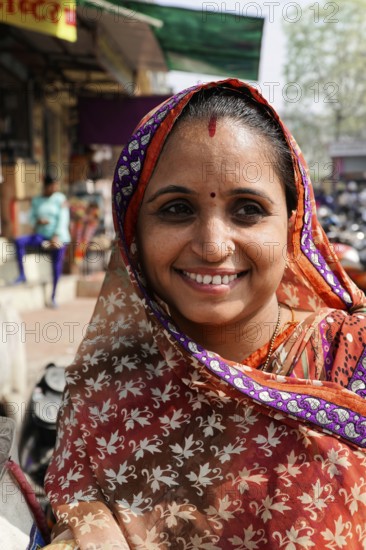 Kota, Rajasthan, North India, Asia, Smiling woman in traditional Indian sari in front of a busy street, India