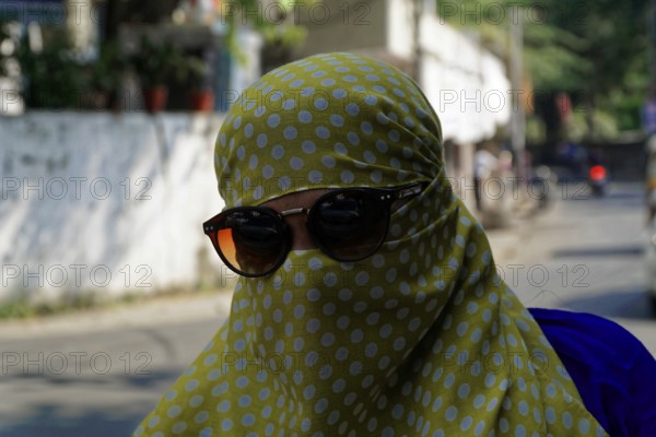 Udaipur, Rajasthan, North India, India, Asia, A woman covered in yellow cloth with sunglasses moves through the city