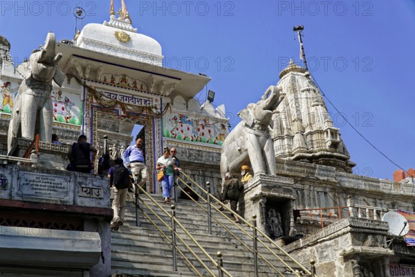Entrance to Jagdish Temple, Udaipur, people climb the steps to a temple flanked by statues under a clear sky, Rajasthan, North India, India, Asia, Temple with imposing elephant sculptures under a clear blue sky
