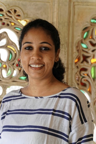 Portrait of a smiling woman in front of ornate, traditional Indian architecture, Udaipur, Rajasthan, North India