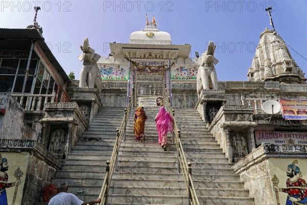 Entrance to Jagdish Temple, Udaipur, People climbing the steps to a temple flanked by statues under a clear sky, Rajasthan, North India, India, Asia, Traditional temple on a hill with majestic elephant statues and colourful murals, Sky clear