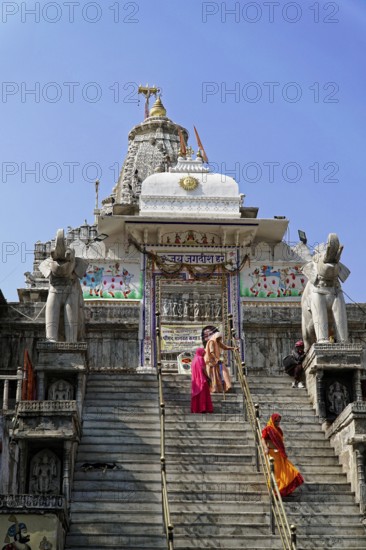 Entrance to Jagdish Temple, Udaipur, people climb the steps to a temple flanked by statues under a clear sky, Rajasthan, North India, India, Asia, Temple with ornate decorative elements and elephant sculptures