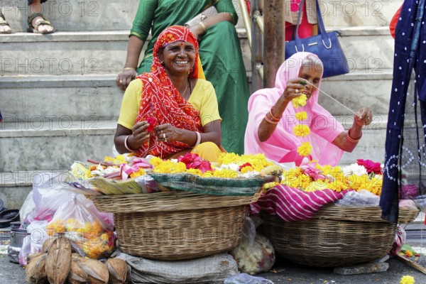 Udaipur, Rajasthan, North India, Asia, Two woman with floral products at a lively market in India