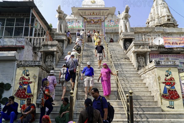 Entrance to Jagdish Temple, Udaipur, People climbing the steps to a temple flanked by statues under a clear sky, Rajasthan, North India, India, Asia, A busy temple in India with numerous visitors walking up and down the stairs
