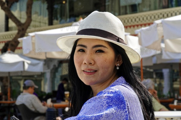 Udaipur, Rajasthan, North India, Asia, A woman in a white hat smiles in an outdoor café