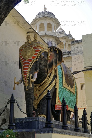 Udaipur, Rajasthan, North India, Asia, Magnificently decorated elephant statue next to an elaborately designed palace building
