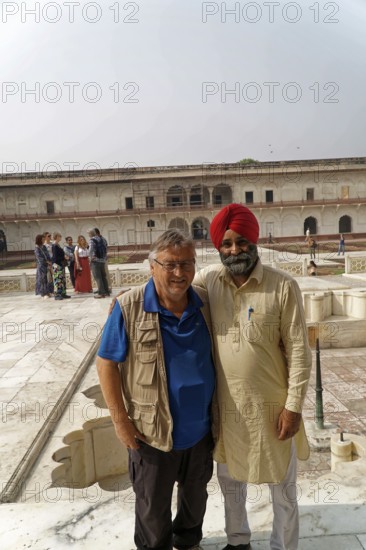 Red Fort, Agra, Uttar Pradesh, India, Two men smile warmly against a historic backdrop while groups stand in the background, Jodhpur, Rajasthan, North India