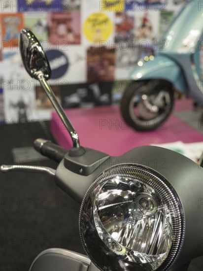 Retro scooter mirror in front of a blurred background with posters and another scooter, dortmund, deutchland