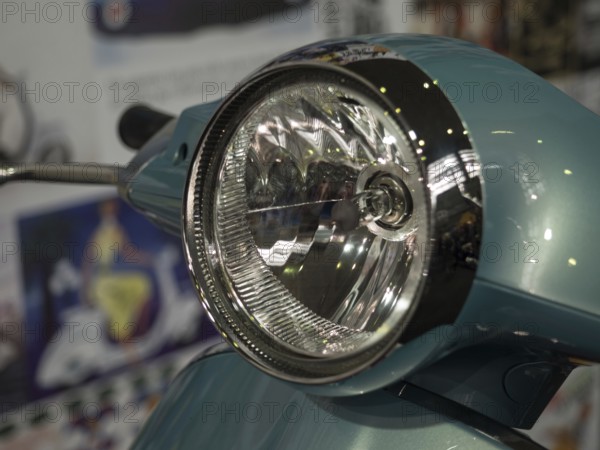 Close-up view of a retro scooter headlight with shiny chrome and a blue housing, dortmund, deutchland