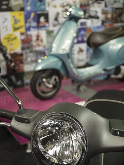 A blue retro scooter stands in an exhibition with posters in the background, dortmund, deutchland