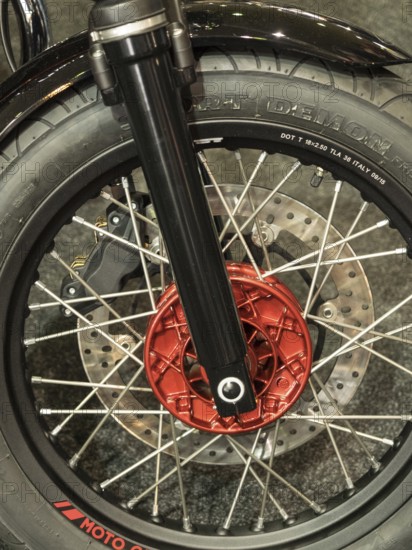 Close-up of a motorbike tyre with red brake caliper and spokes on dark ground, dortmund, germany
