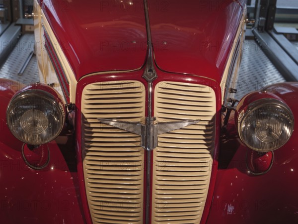 Front view of a red classic car, emphasising the radiator grille and round headlights, Cologne, Germany