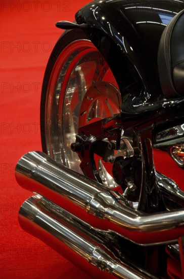 Exhaust system of a black motorbike against a red background, emphasising elegant lines, dortmund, germany