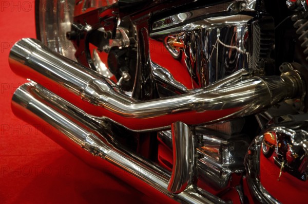 Close-up of a shiny exhaust system in chrome with red background, dortmund, germany