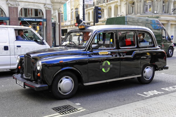 Black taxi driving on a busy London street in daylight, London, London region, England, United Kingdom