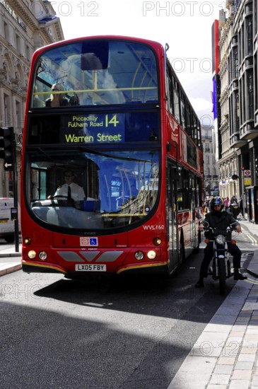 Red double-decker bus travelling along a busy London street, London, London region, England, United Kingdom