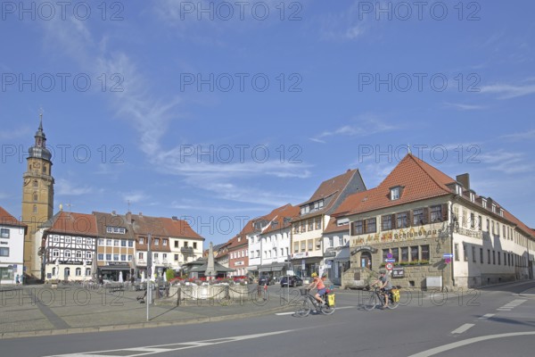Market square with historic Schlundhaus, cyclist, steeple of the Church of the Assumption of the Virgin Mary, Bad Königshofen, Rhön, Lower Franconia, Franconia, Bavaria, Germany