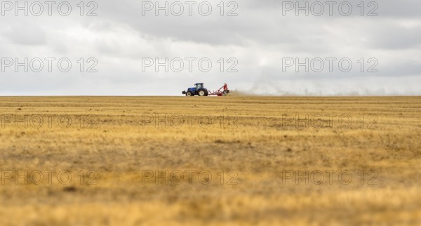 Stormy farmland scenery showing a Tractor on a stubble field in Hohenlohe, an area in Southern Germany at late summer time