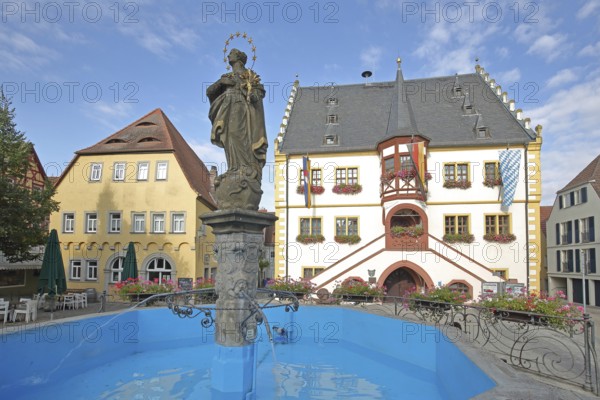 Madonna figure at the market fountain, Renaissance town hall with town flag, Bavarian state flag and German national flag, blue water basin, market square, Volkach, Lower Franconia, Franconia, Bavaria, Germany
