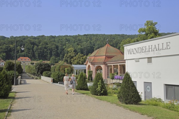 Pedestrians in the spa gardens with Wandelhalle, Wernarz spring temple and view of Fürstenhof, path, inscription, state bath, Bad Brückenau, Rhön, Bavaria, Germany