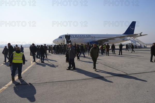 Passengers celebrate with Syrian revolutionary flags as the first flight lands at Aleppo International Airport in the presence of government officials following the fall of Bashar al-Assad's regime. Aleppo, Syria. December 18, 2024, Aleppo, Aleppo, Syria