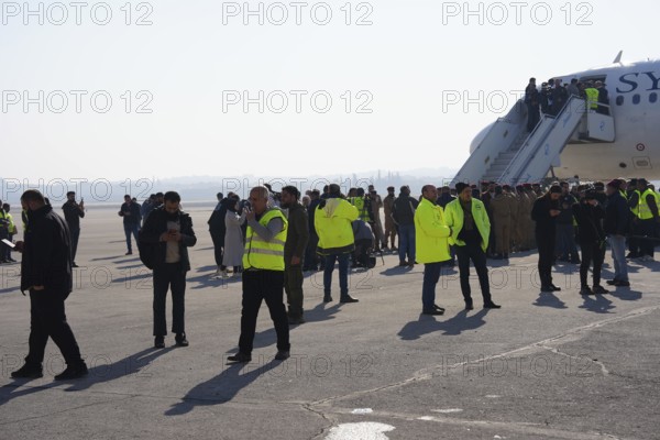 Passengers celebrate with Syrian revolutionary flags as the first flight lands at Aleppo International Airport in the presence of government officials following the fall of Bashar al-Assad's regime. Aleppo, Syria. December 18, 2024, Aleppo, Aleppo, Syria