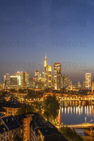 Illuminated Frankfurt City Skyline, Residential Buildings, Bridges and Main River at Night. Wide Shot. Aerial View. Blue Hour. Hesse, Germany