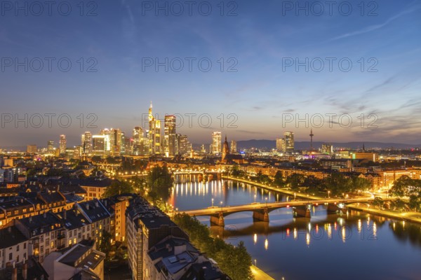 Illuminated Frankfurt City Downtown, Residential Buildings, Bridges and Main River at Night. Wide Shot. Aerial View. Blue Hour. Hesse, Germany