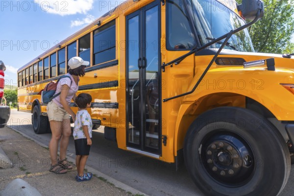 Caring mother supports her son as he prepares to board the school bus for his first day back to school, marking a significant milestone in his education
