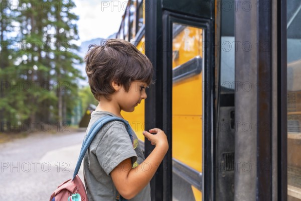 Curious preschool student with a backpack examines a yellow school bus before boarding, showing the anticipation and excitement of going back to school