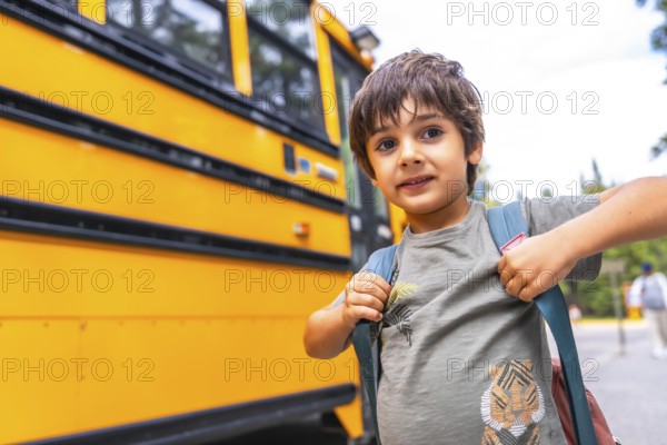 Elementary school student wearing a backpack, waiting for the bus on a bright, sunny day, excitedly heading to school for a day of learning and adventure