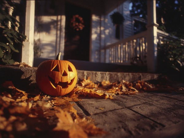 A carved pumpkin with a smiling face stands on a house wall in front of a residential building, symbolising Halloween and autumnal mood, AI generated, AI generated
