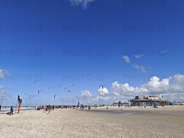 California kitesurfing Masters 2025 on the edge of the Wadden Sea UNESCO World Heritage Site, North Sea, beach, kitesurfing, sport, leisure, spectators, pile dwelling, summer, sun, blue sky, white clouds, Ording, Sankt Peter-Ording, Schleswig-Holstein, Germany