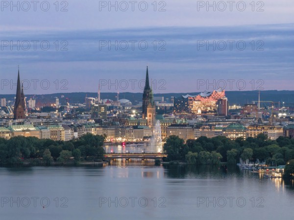 Aerial view of the Outer Alster and Binnenslater at dusk during the Blue Hour with illuminated Elbphilharmonie, City Hall, Alster Fountain, Jungfernstieg, Kennedy Bridge and churches, Hamburg, Germany
