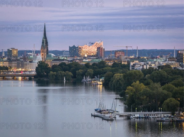 Aerial view of the Outer Alster and Binnenslater at dusk during the Blue Hour with illuminated Elbphilharmonie, City Hall, Alster Fountain, Jungfernstieg, Kennedy Bridge, jetty and churches, Hamburg, Germany
