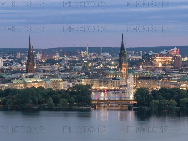 Aerial view of the Outer Alster and Binnenslater at dusk during the Blue Hour with illuminated Elbphilharmonie, City Hall, Alster Fountain, Jungfernstieg, Kennedy Bridge and churches, Hamburg, Germany