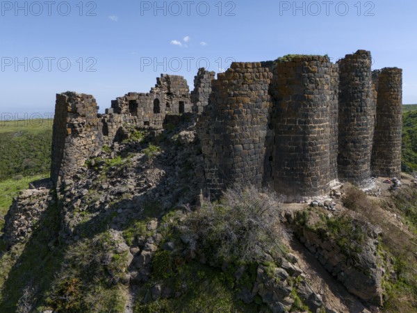 Massive ruins of a stone tower on a hill in nature, aerial view, Amberd Fortress, Aragazotn Province, Armenia