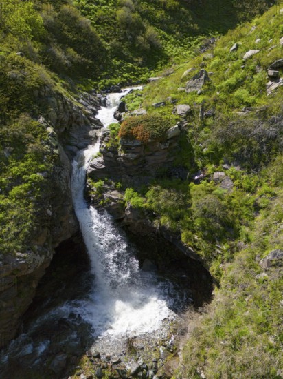 Waterfall between rocks and green vegetation in a mountain landscape, aerial view, waterfall near Amberd, Aragazotn province, Armenia