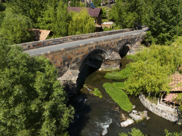 Aerial view of an old stone bridge over a winding river in green nature, aerial view, bridge from 1705 over the Kassagh, Oskahan, Oshakan, Ošakan, Aragazotn Province, Armenia