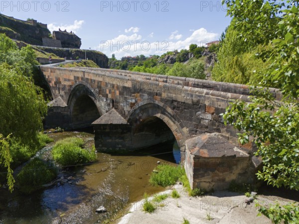 Old stone bridge with two arches over a flowing river under a clear sky, aerial view, bridge from 1705 over the Kassagh, Oskahan, Oshakan, Ošakan, Aragazotn province, Armenia