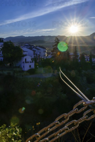 Steel cables and chains stretch towards the picturesque town of ronda, spain, bathed in the golden light of a setting sun in ronda, malaga, spain