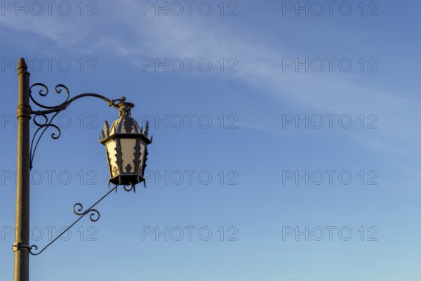Ornate street lamp with wrought iron detail stands against a clear blue sky in ronda, malaga, spain