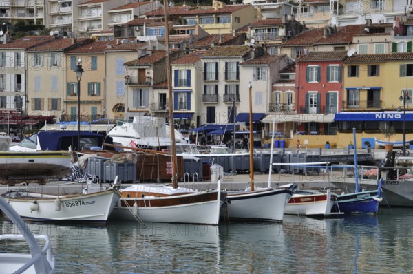 Cassis, the port, Boats docked in a harbor with colorful buildings lining the waterfront on an overcast day
