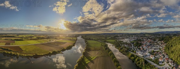 The sunset bathes the river landscape of the Danube in a warm light. A few fields and meadows border the calm water. The sky is partly cloudy and radiates a peaceful atmosphere. Bogen, Lower Bavaria